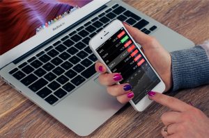 Woman holding iPhone showing stock values in red, in a financial crisis